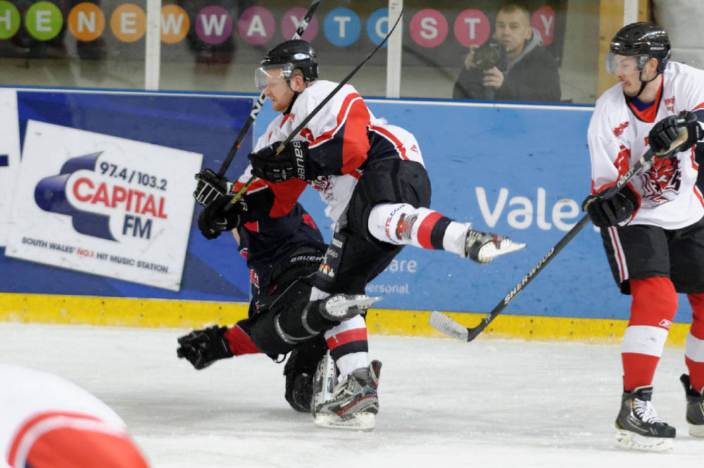 two men playing in ice hockey on an indoor rink