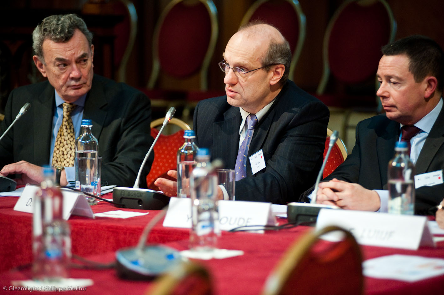 four men sit at a conference table with their beverages