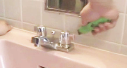 a persons hand holding a green handled hair brush