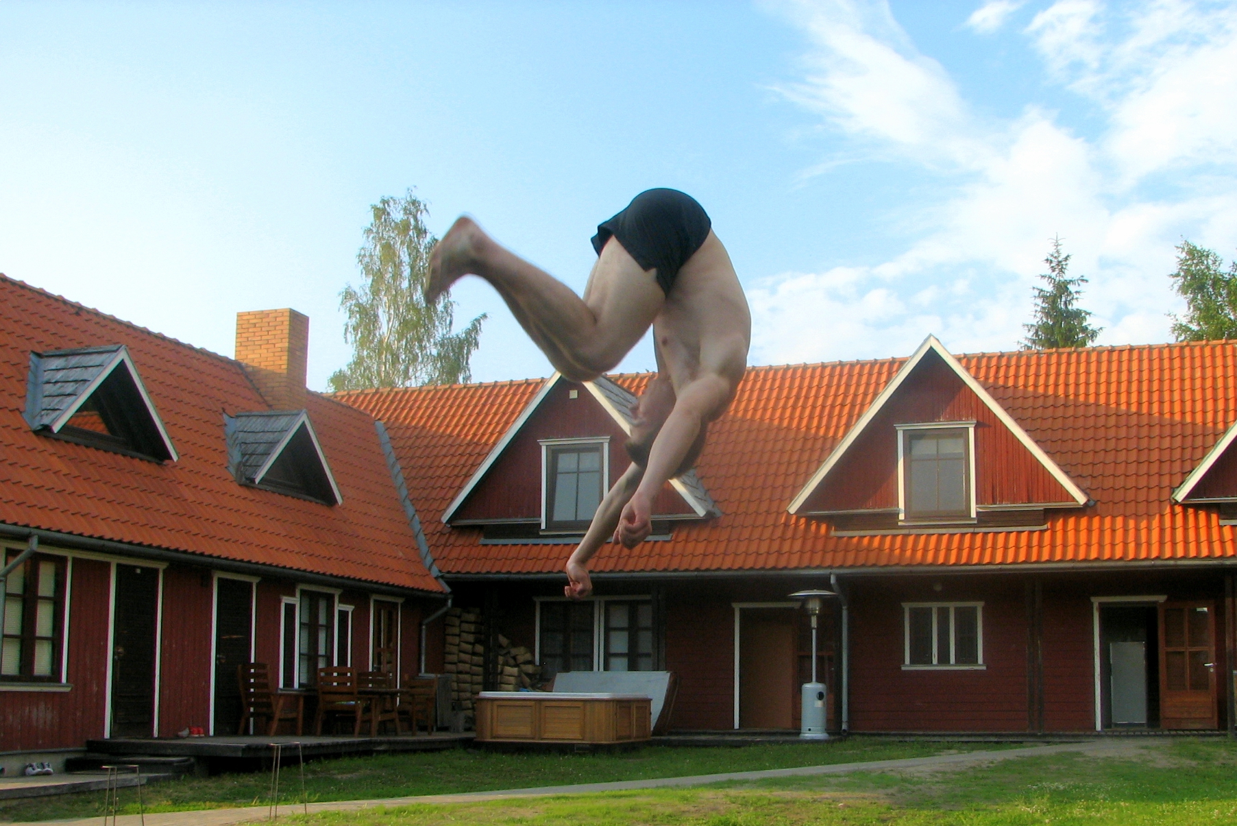 a man diving into the air in front of an orange roof