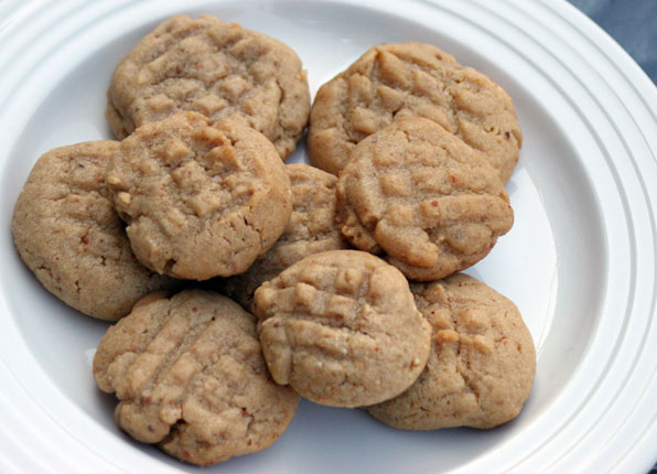 five cookies with peanut er on top in a white bowl