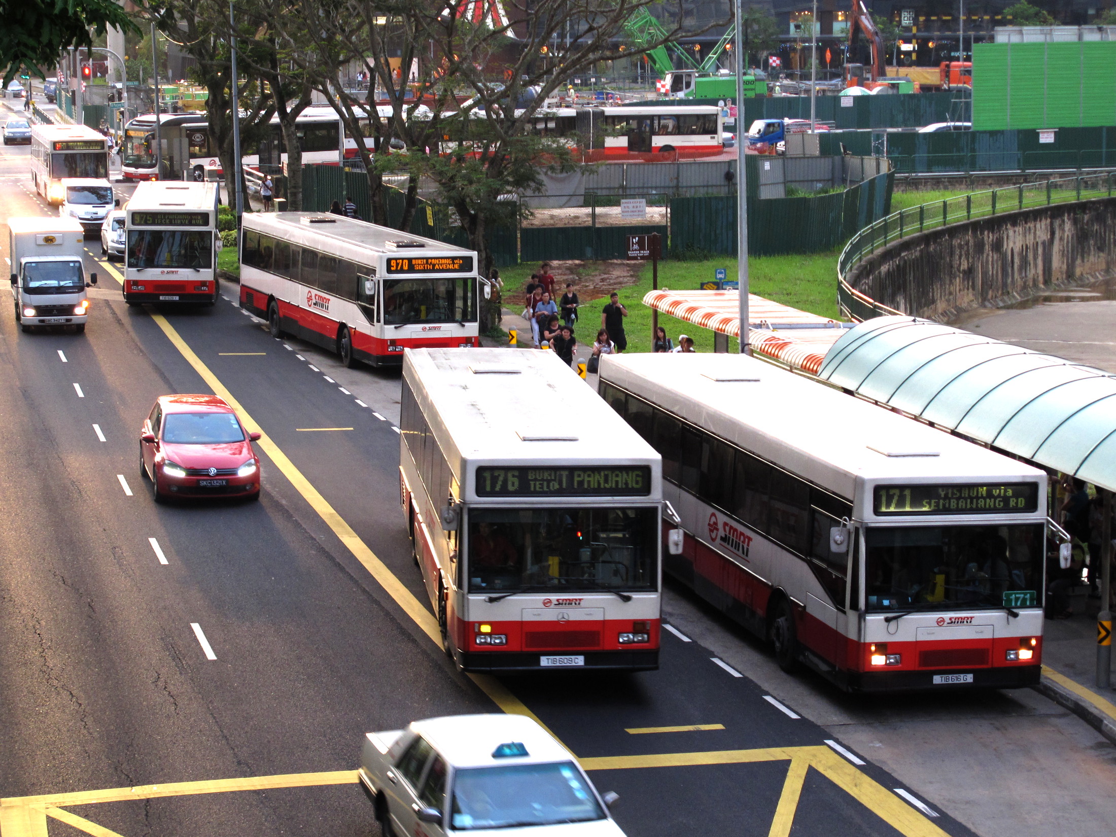 the street scene has two buses, three cars, and one van