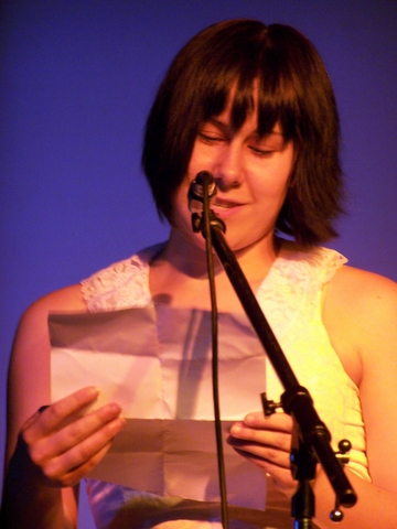a woman holding a microphone and wearing a white top