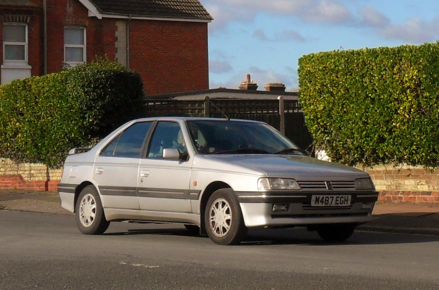 an older silver car is driving on the street