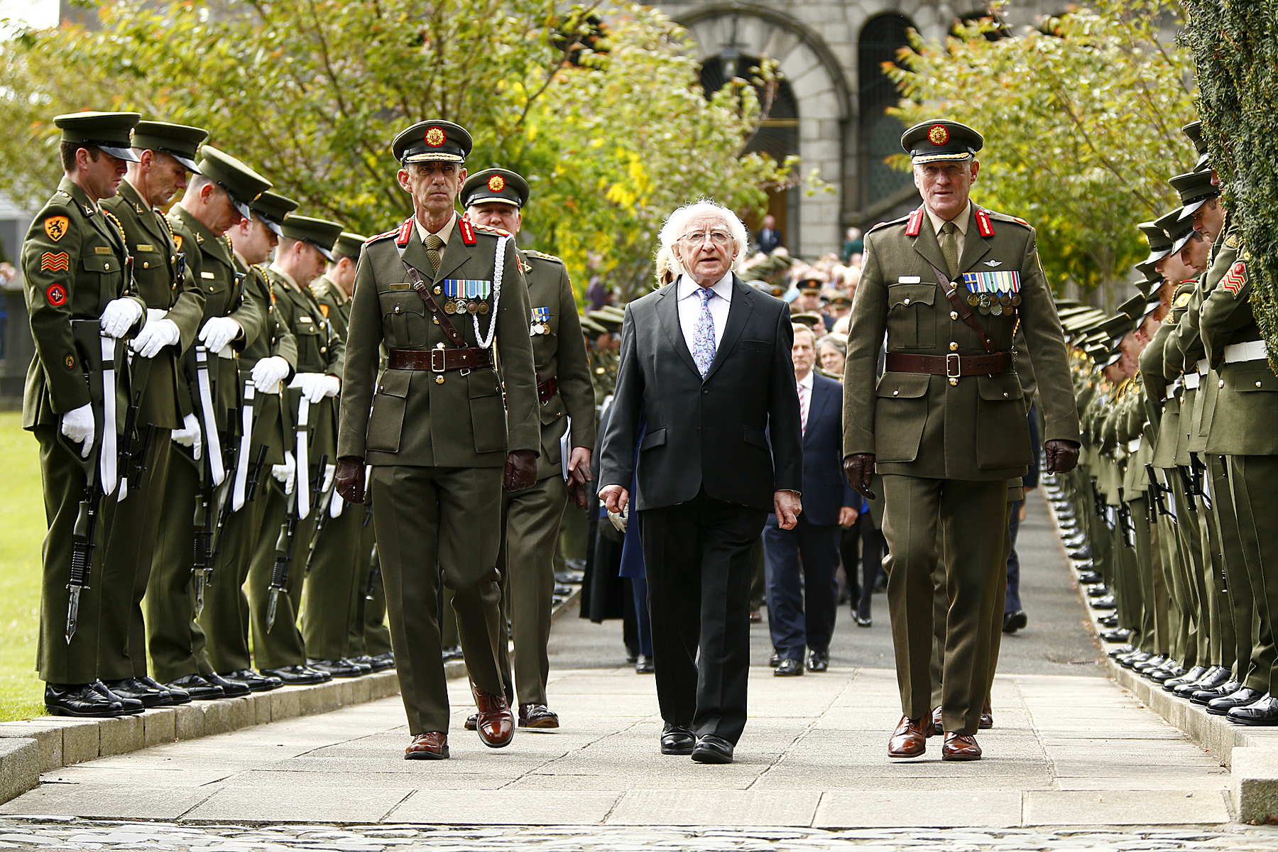 several people in uniforms walking down a sidewalk