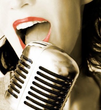woman with makeup and long nails holding a silver microphone