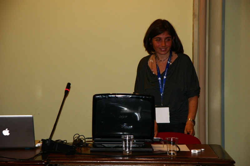 a woman standing next to a desk with a laptop