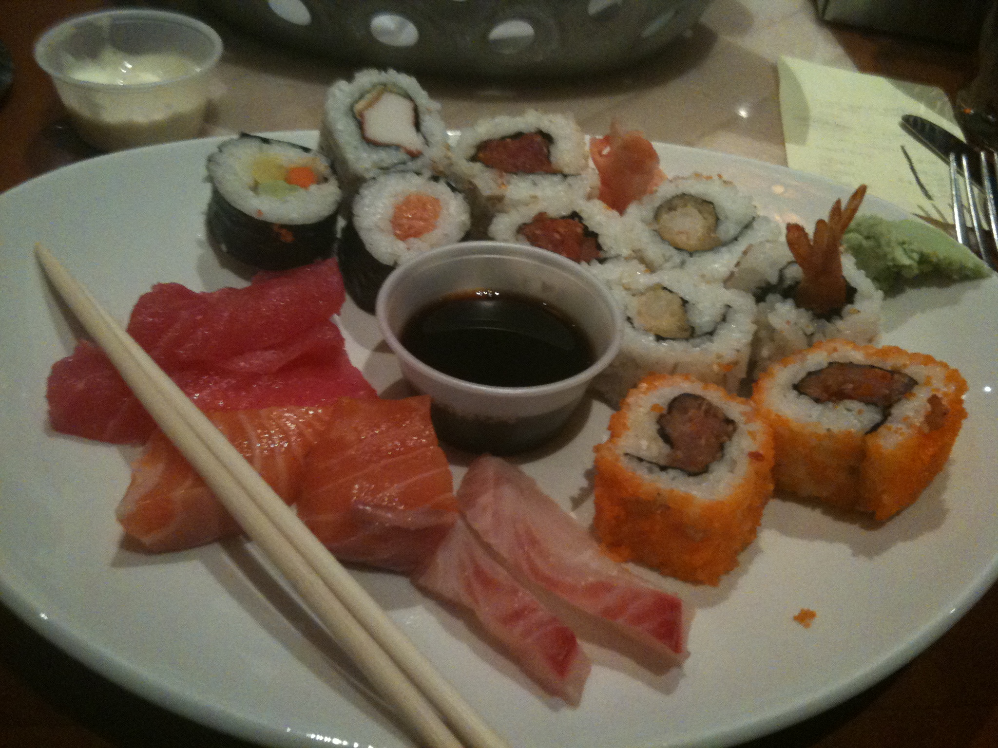 sushi and rolls sitting on a white plate with chopsticks