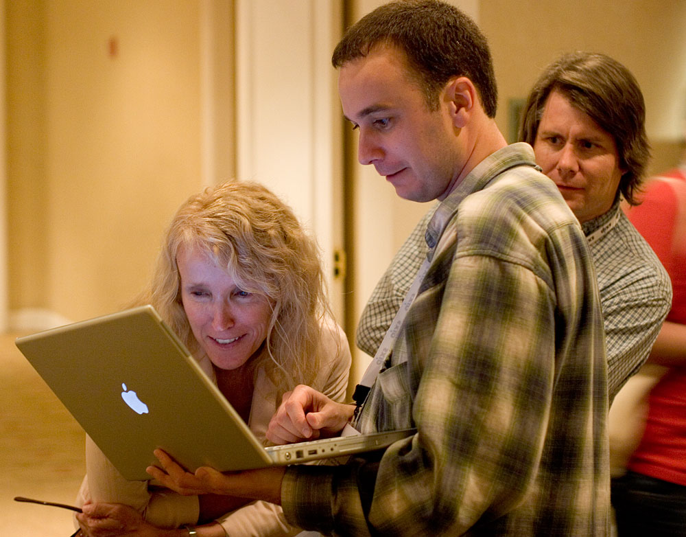 two people and a woman on their lap top in a room