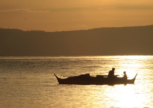 two people in a small boat sailing on a river at sunset