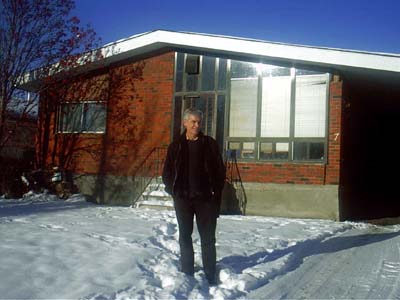 man standing on the snow in front of a building