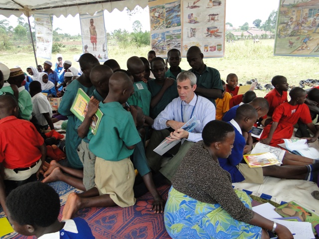 a man in a green shirt sitting on a chair talking to other people