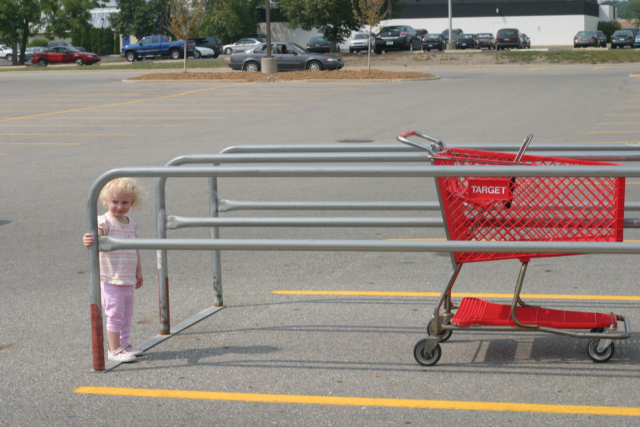 a little girl standing in the parking lot at an grocery store