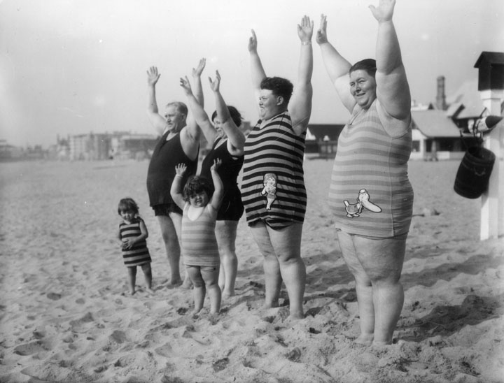 a black and white po of a man holding his arms up as a group of children stand on the beach