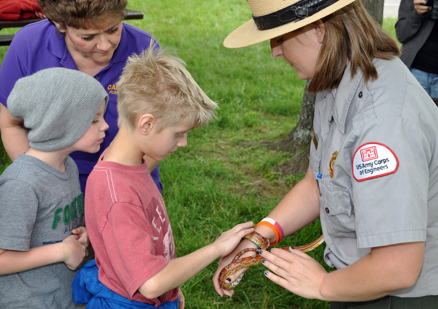 there is a woman standing over a  that is holding a snake