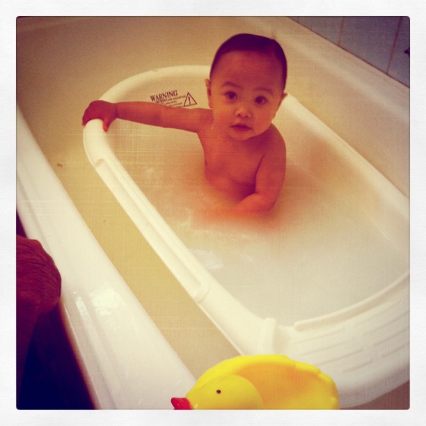 a little boy sits in a tub with a rubber duck