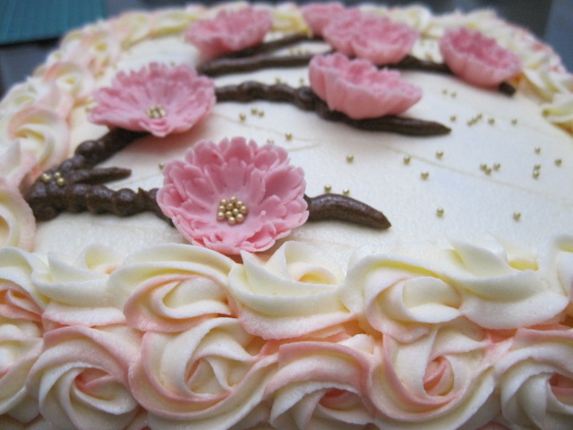 there is a frosted cake with pink flowers on top