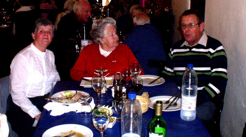 three people sitting at the table with wine glasses and food