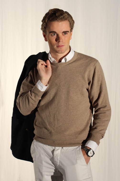a man wearing a brown sweater and white pants