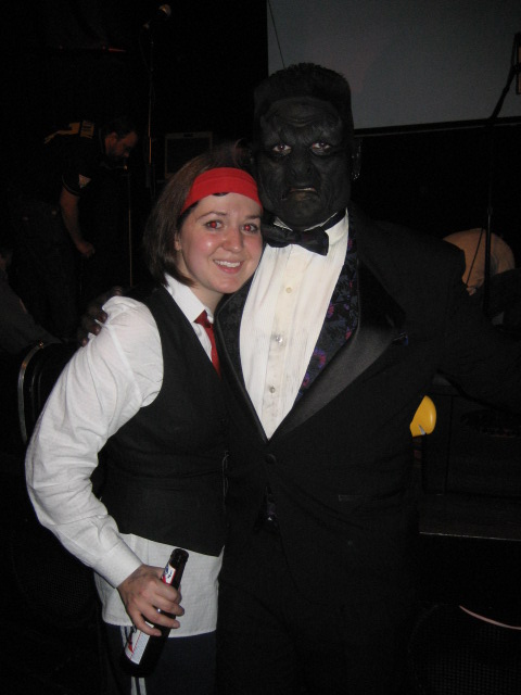 a man in a suit and tie next to a woman dressed in a costume