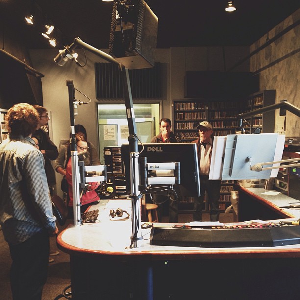 a recording crew stands at a desk talking