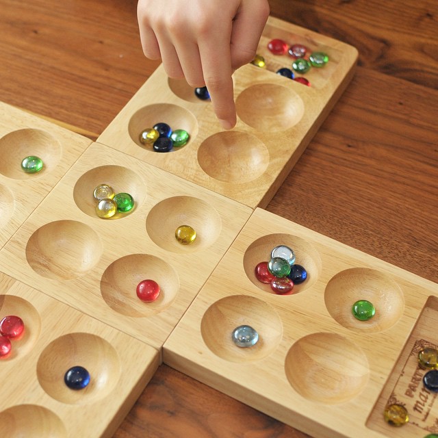 a child using marbles to play with two matching trays