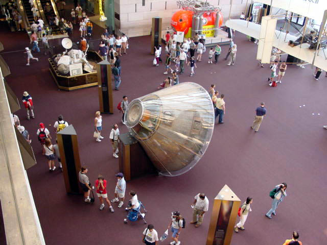 large metallic object next to many people on a street