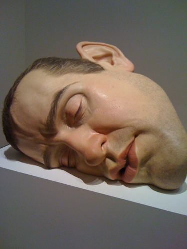 a sculpture with his eyes closed lying on a ledge