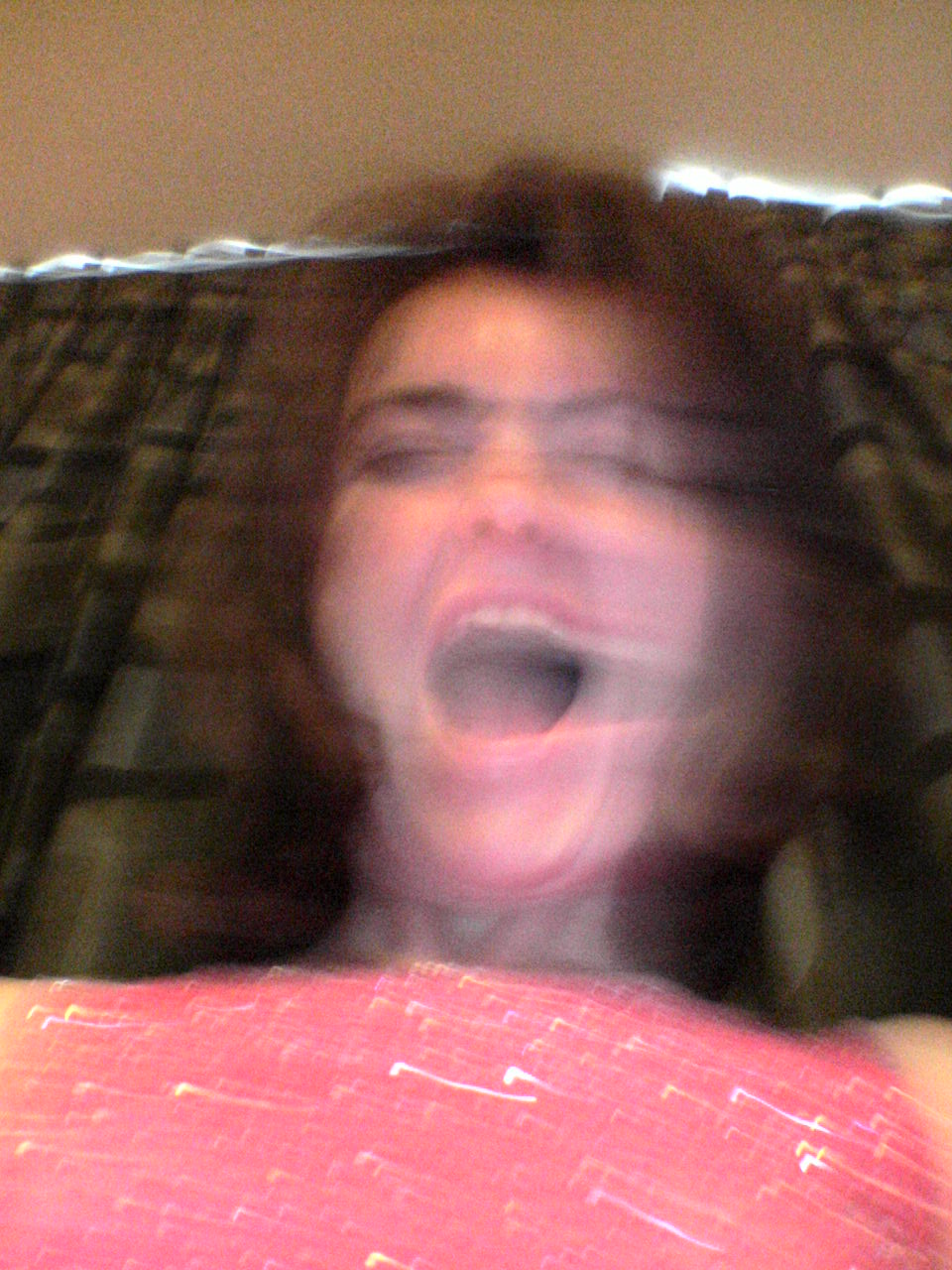 woman shouting while sitting on a bed with a blanket