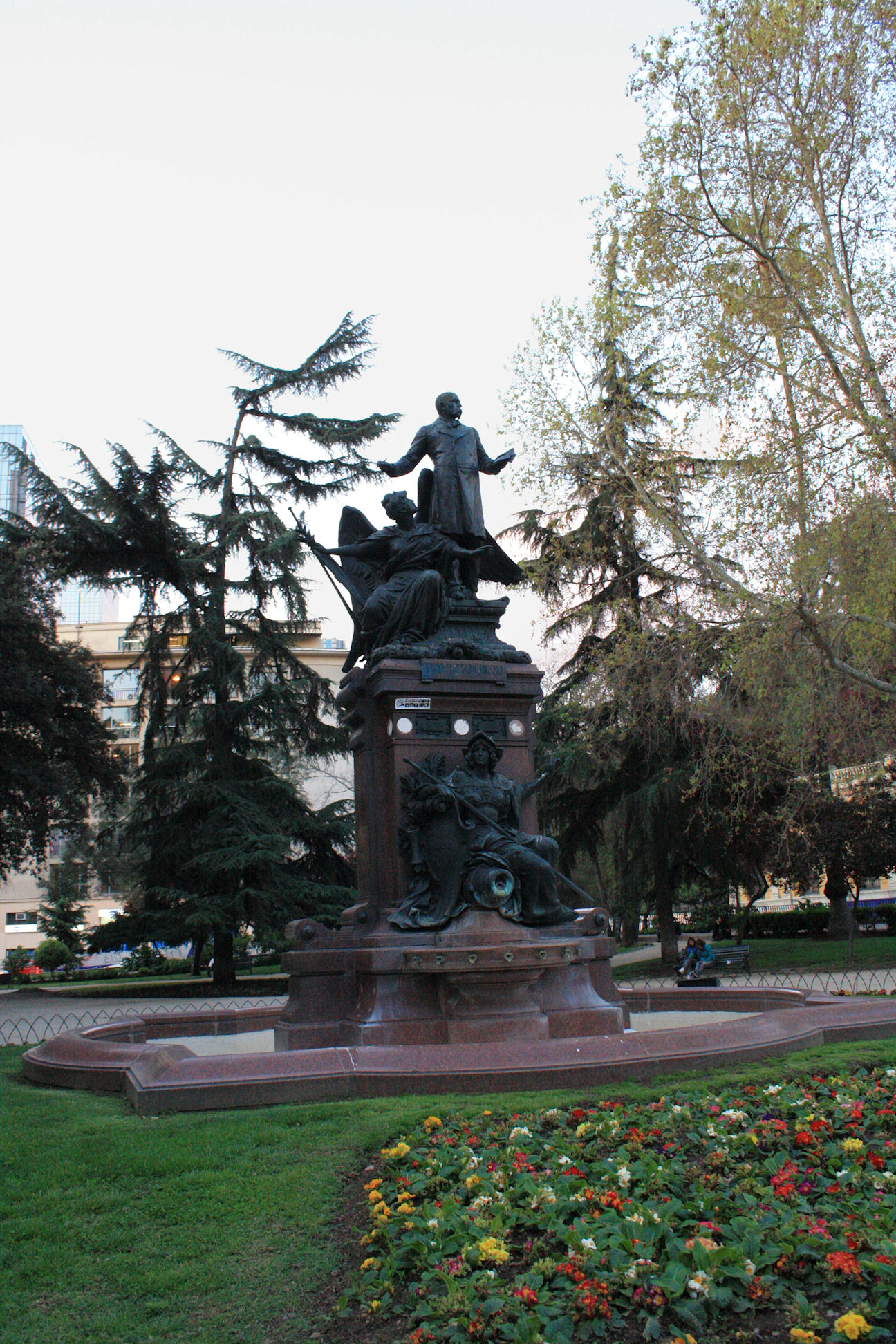 a small statue sitting in the middle of a garden