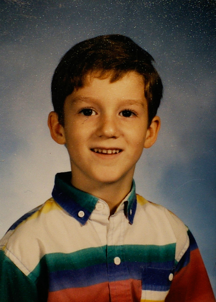 a close up of a smiling boy wearing a shirt