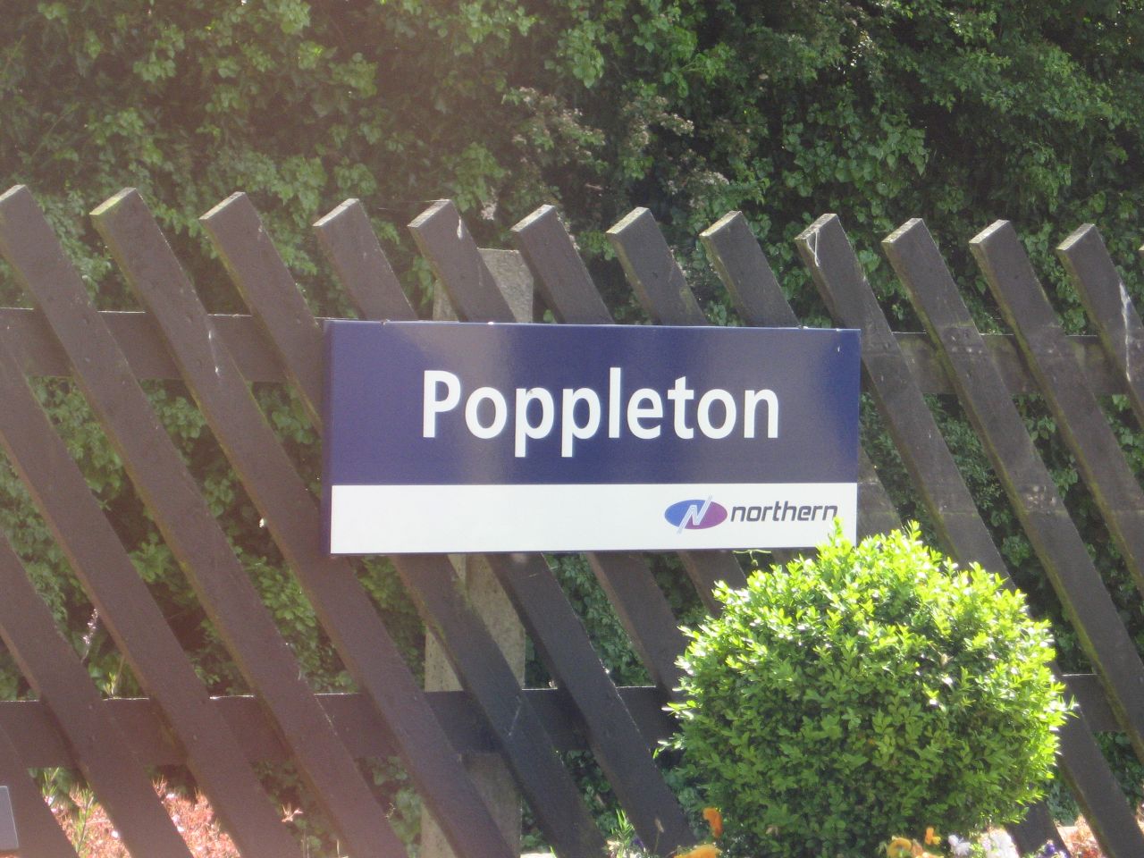 sign that says poppleton above wooden fence
