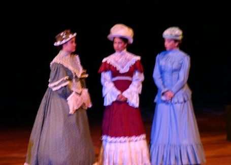 three people standing on a stage dressed in costumes