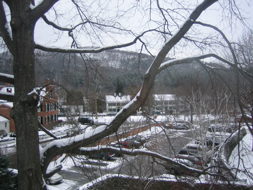 snowy parking lot with many vehicles and buildings
