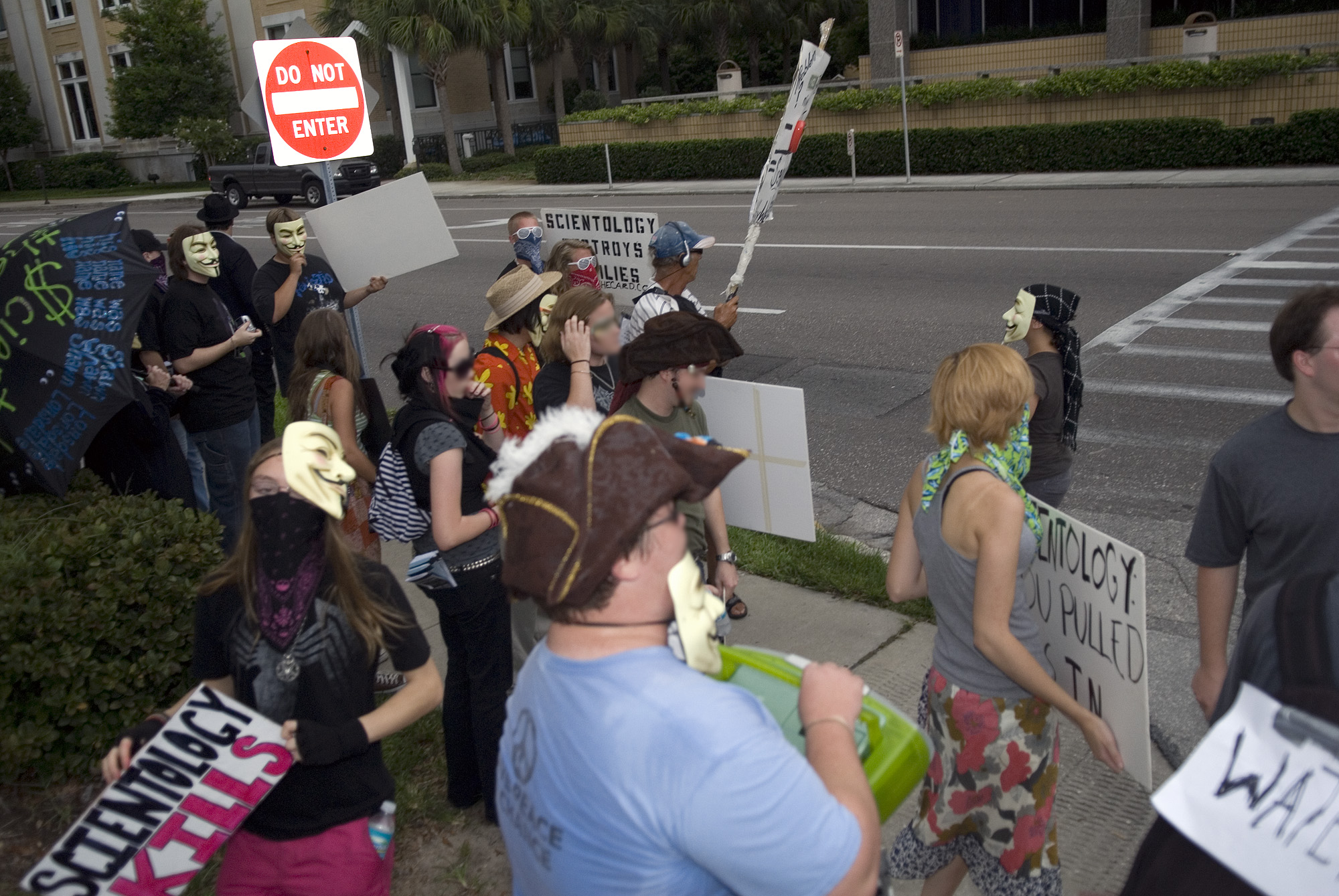 a group of people with face painted costumes holding signs on the side of a road