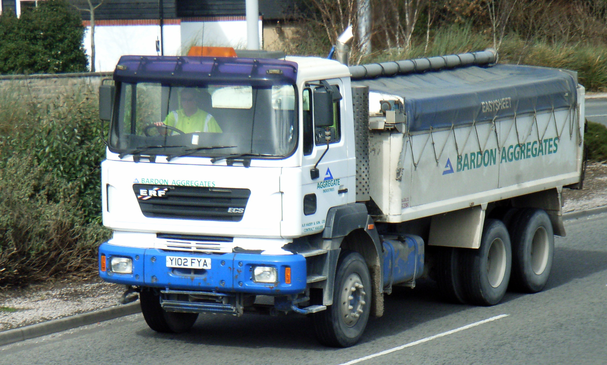 a blue and white truck driving on the side of a street