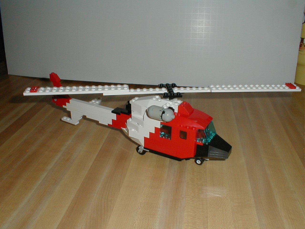 a lego helicopter sits on the floor with a ladder down