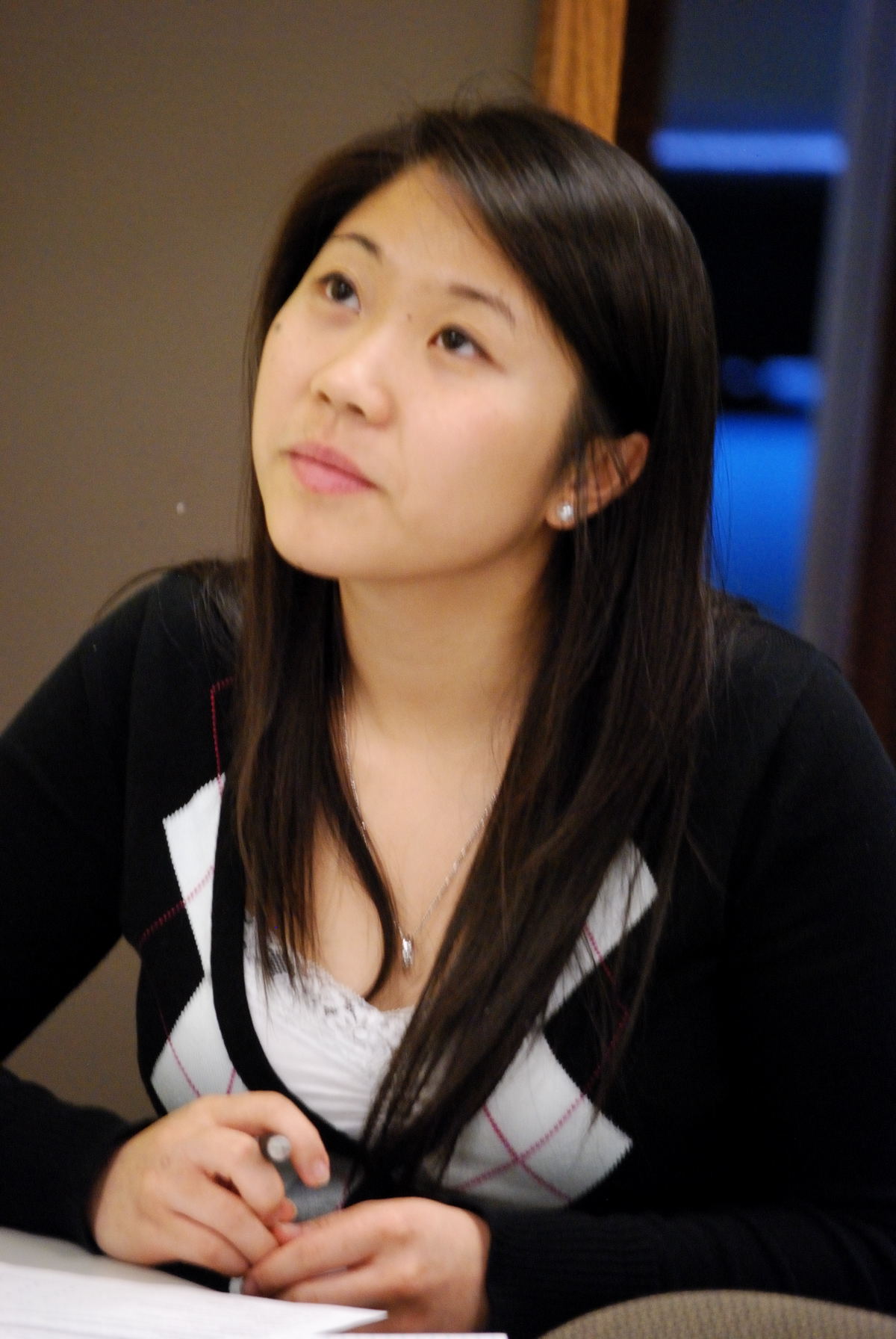 asian girl sitting at table with book staring off to the side