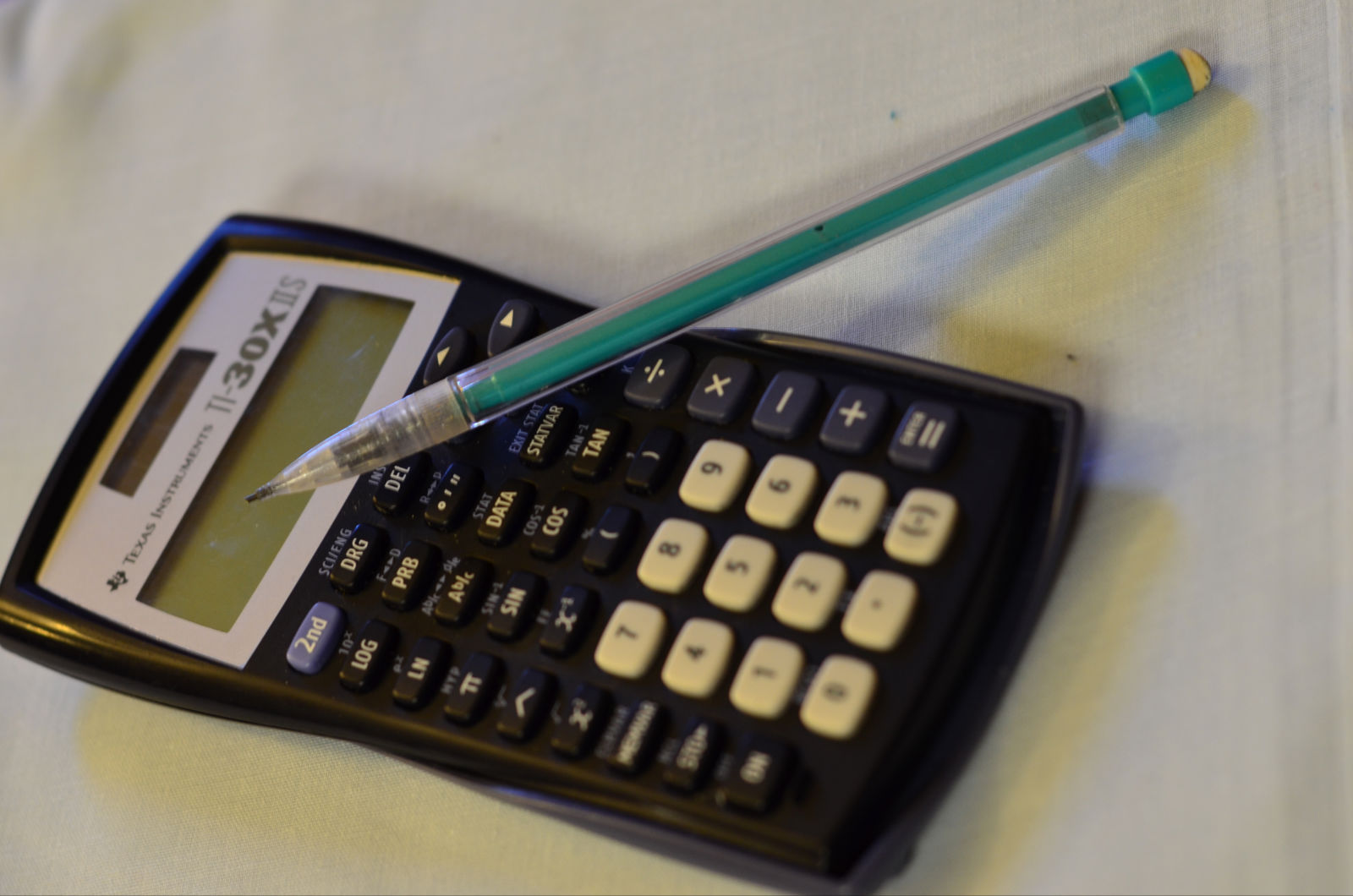 a pen and a calculator sit on a table