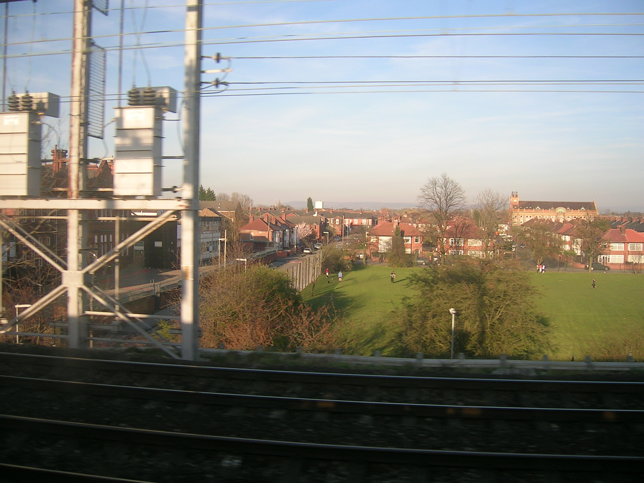 a train travels along the tracks past several buildings and a green field