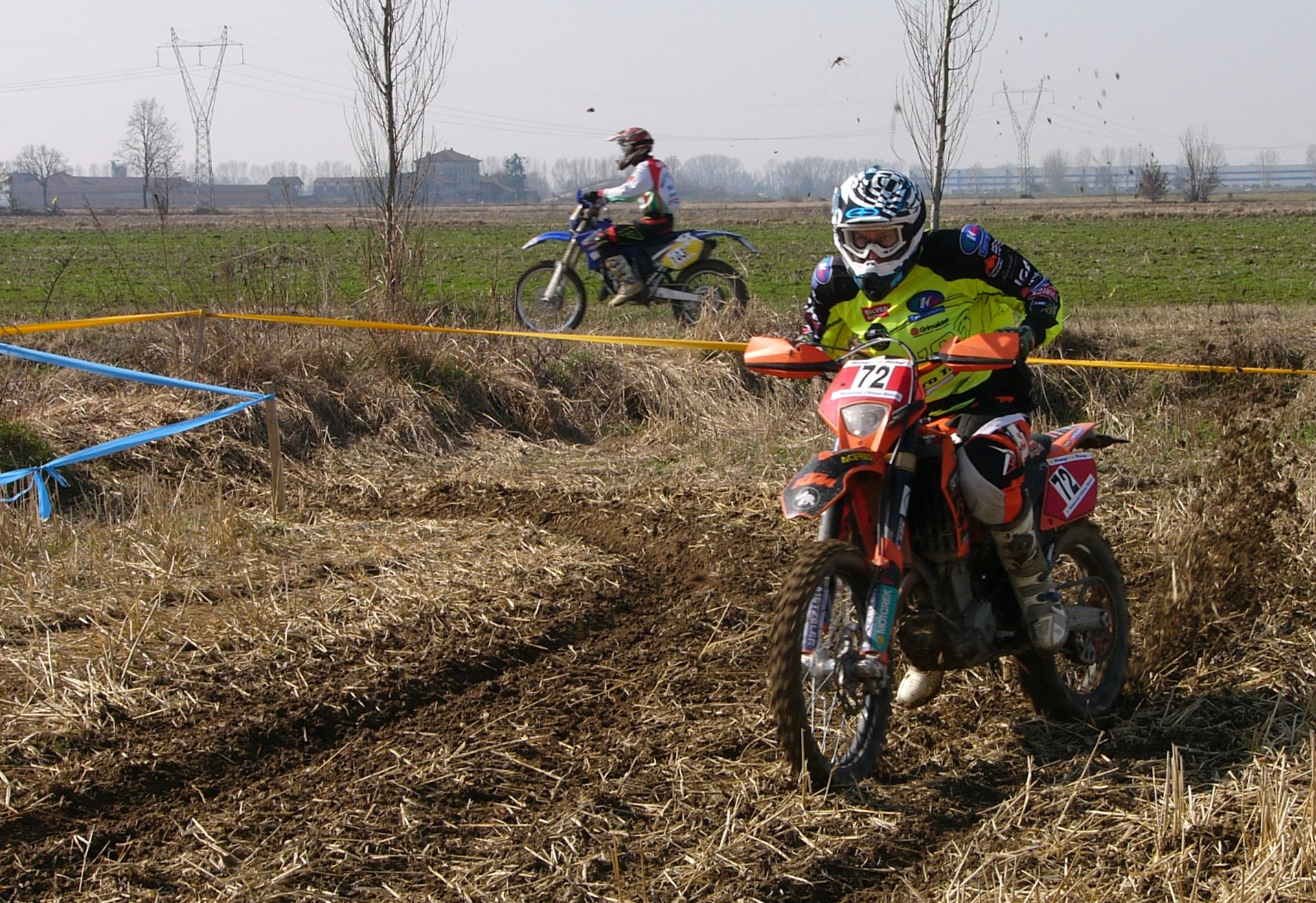 two people on motorcycles riding in the dirt
