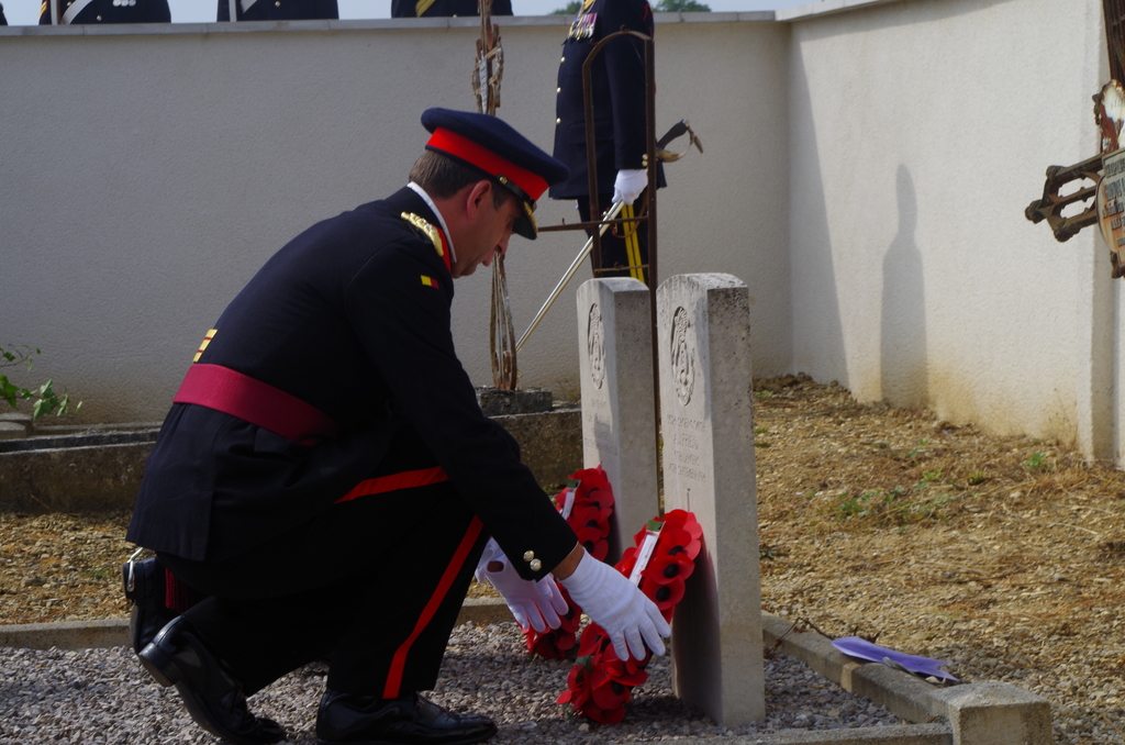 a man kneeling down touching a cross on a memorial