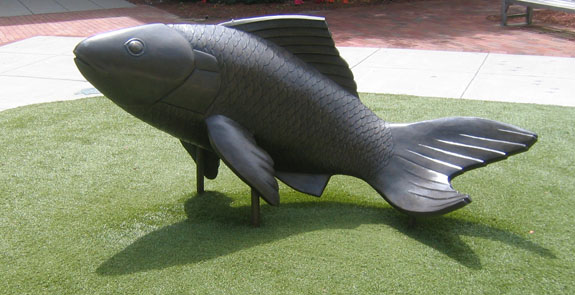 a very big fish statue in the grass
