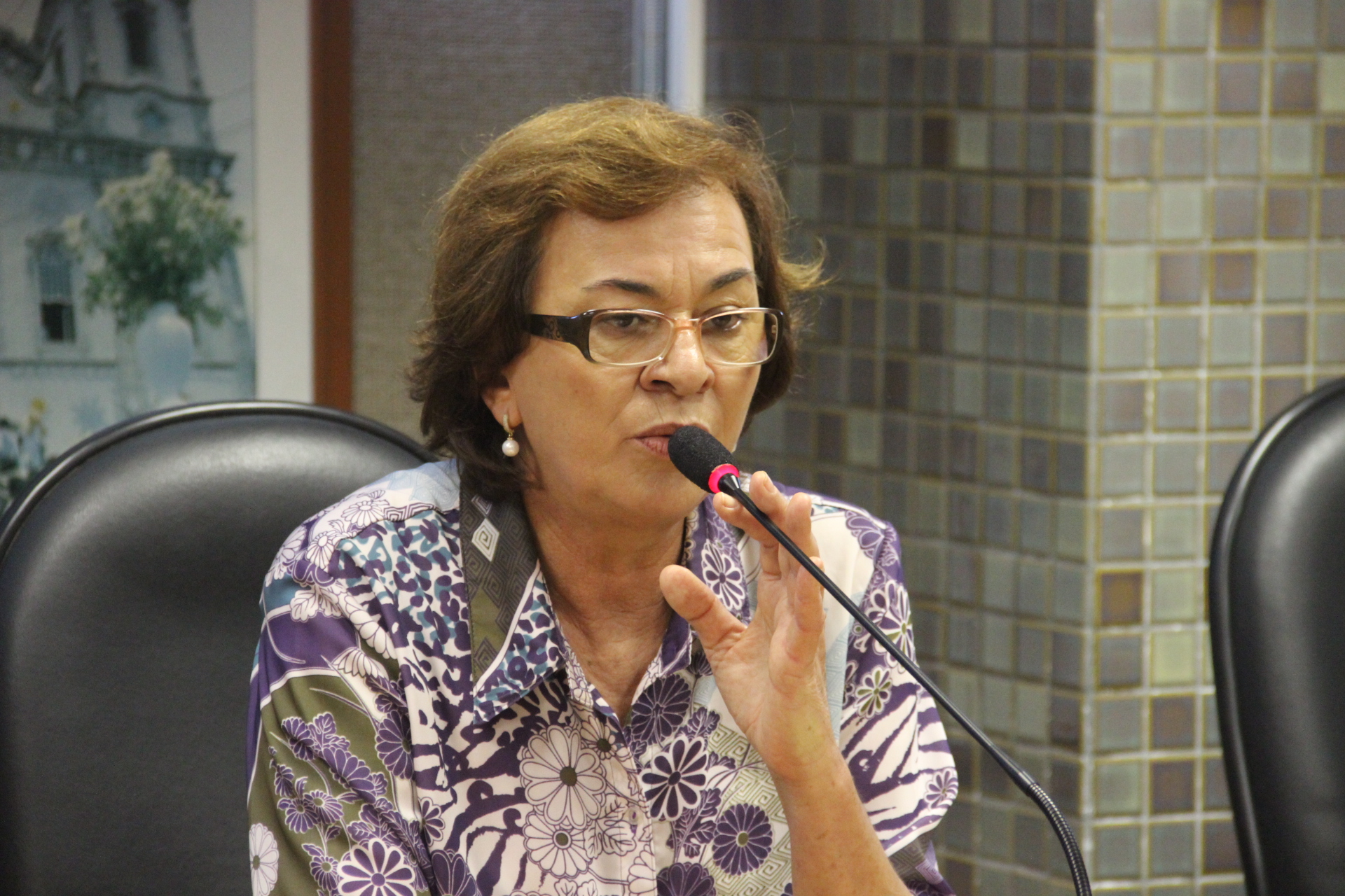 a woman wearing glasses speaking into a microphone