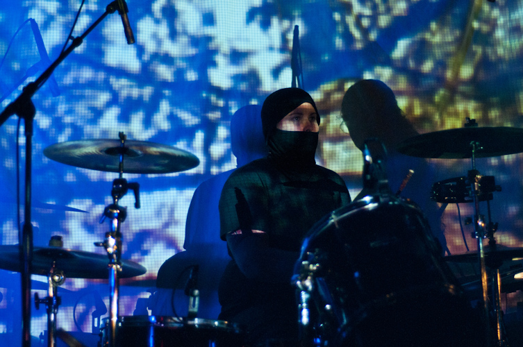 a man with a hood is playing the drums