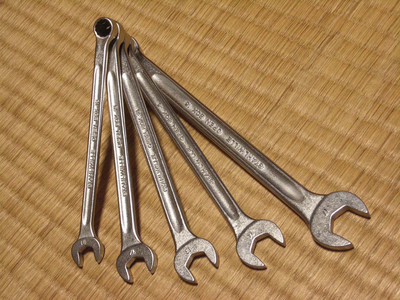 six wrenches laid on top of a piece of wood