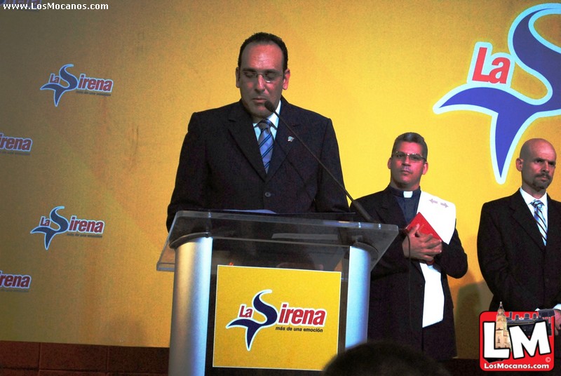 two men standing at a podium behind a man holding a small book