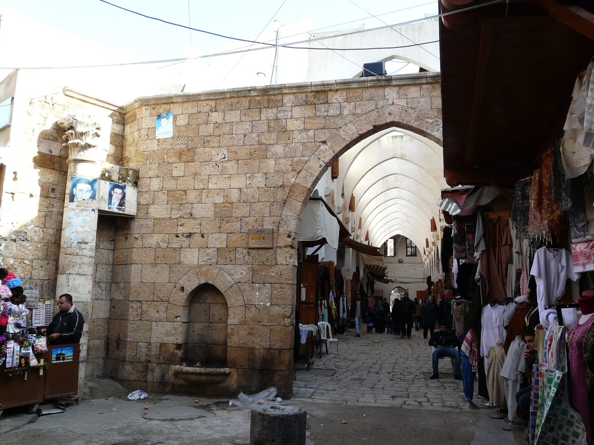 a narrow alley with people shopping and onlookers