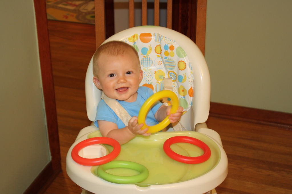 baby sitting in high chair smiling at the camera