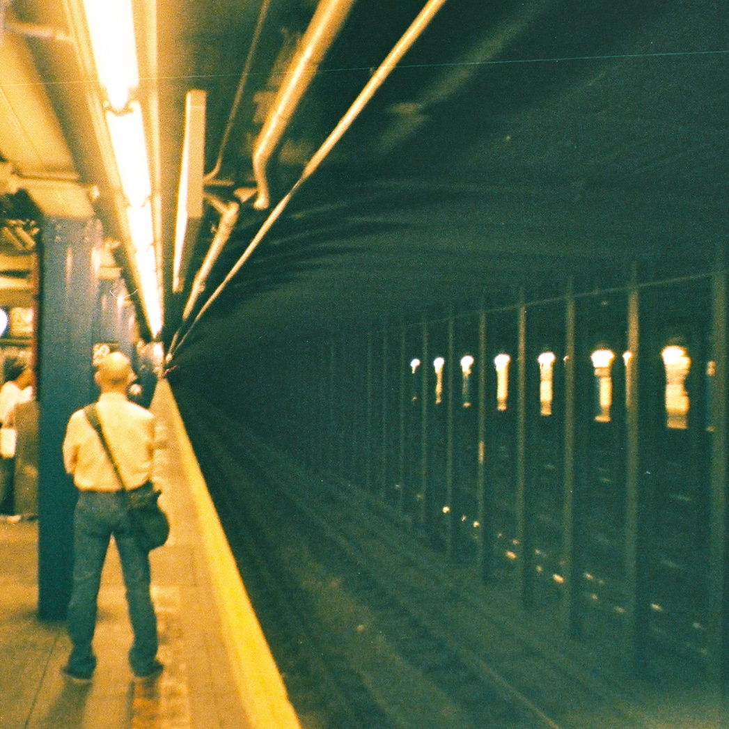 there is a man standing on the platform at the subway station